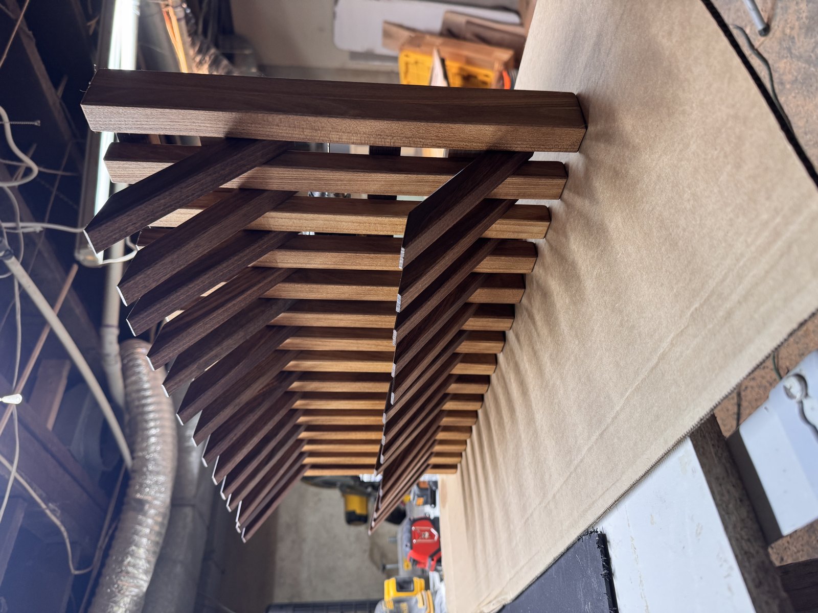 Double-tier walnut flip-down wall rack with hooks out, side profile in the shop